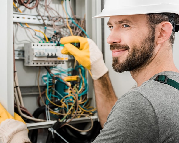 Man smiling while working on an electric box